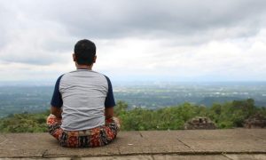 IMG-20170121-WA0091 Young man sits cross-legged on stone ledge