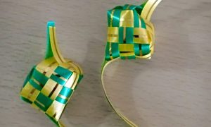Handwoven green and yellow woven basket sits on plain surface
