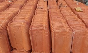 Stacks of terracotta roof tiles arranged neatly in rows