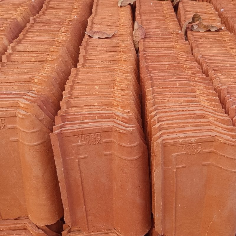 Stacks of terracotta roof tiles arranged neatly in rows