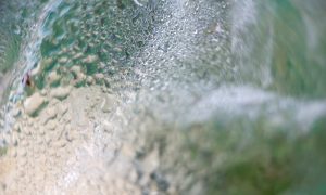 Ocean wave crashes, bubbles burst, water churns